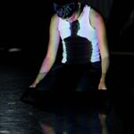 Dance_Grad_Show_24_BH_hi-res_AWAITING_APPROVAL_14_rgb A dancer wearing a white top performs with shadows projected onto their body