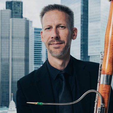 Graham-Hobbs--aspect-ratio-750-750 Graham Hobbs is a white man with short hair. He is wearing a dark coloured suit and holding a bassoon.