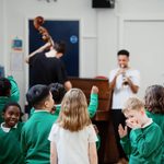 A group of school children listen to jazz music played by Trinity Laban undergraduate students.
